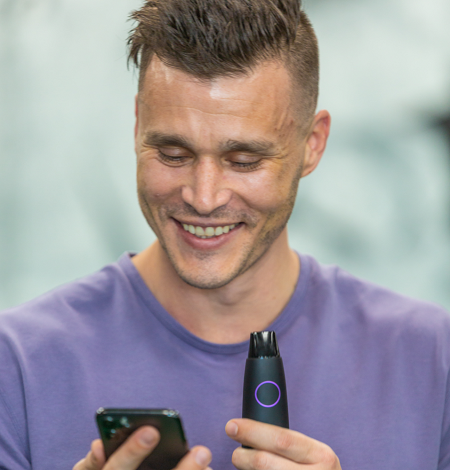 A smiling man with a lumen device in hand looking at a cell phone
